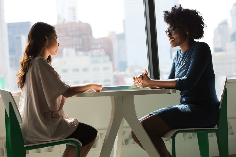 two ladies sat across a table from each other at a window